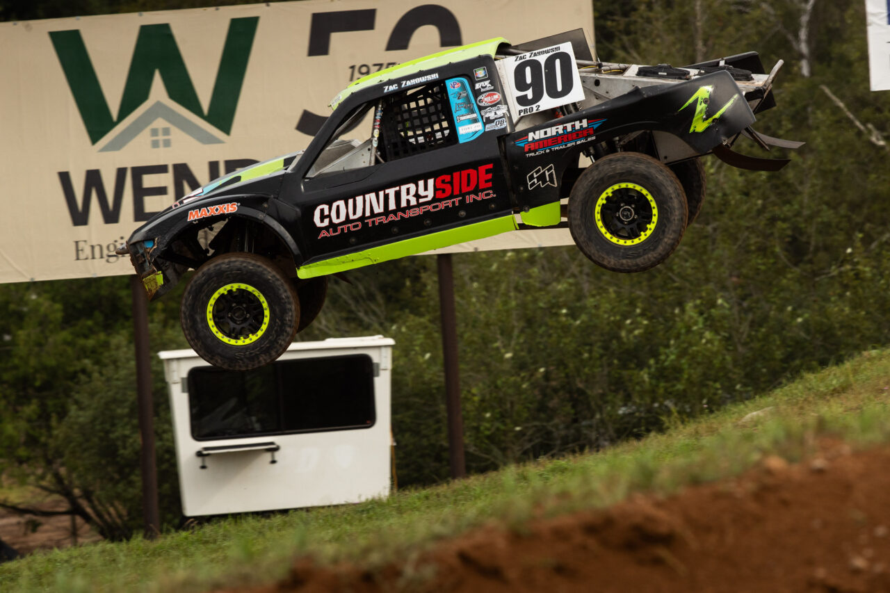 Kyle Chaney in his Black and yellow Pro4 race truck sailing over a jump at Bark River.