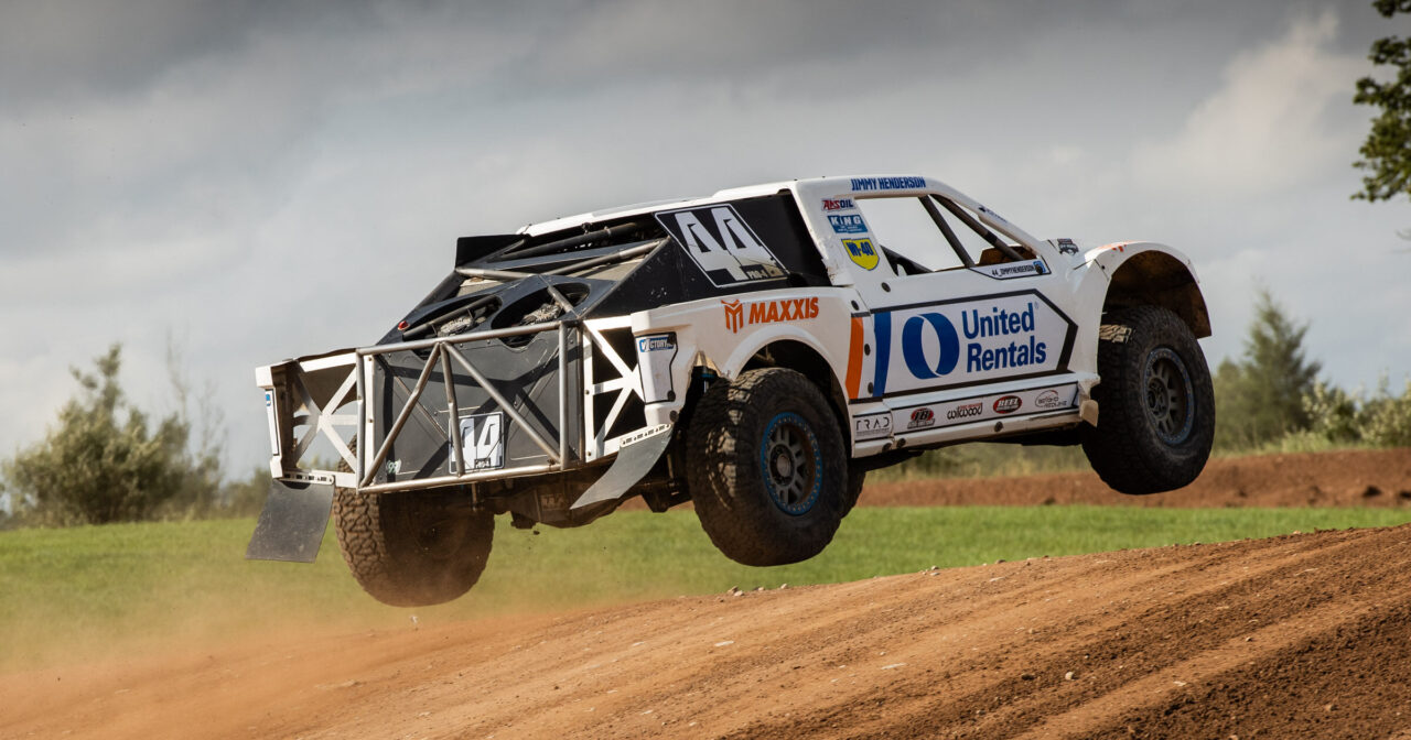 white truck jumping over a dirt jump.