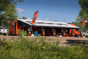 A large orange Maxxis-branded support trailer is set up at an outdoor racing event.