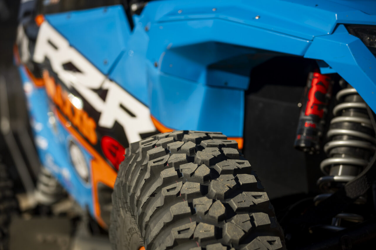 the top of a Maxxis Roxxzilla tire with a powder blue body of a SxS in the back ground.