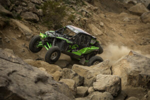 A green and black SxS navigating larger boulders on Maxxis' Super Knobby Roxxzillas.