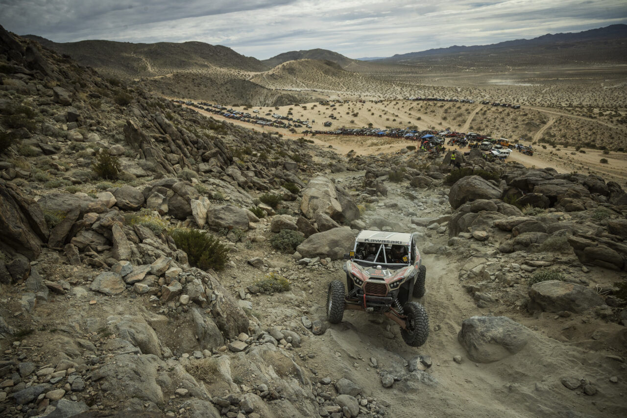 Maxxis athlete Jeremy McGrath racing up a rocky path in his red and black KRX SxS.