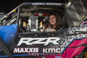 Sierra Romo smiling while sitting, helmet off, in her Polaris RZR race car.