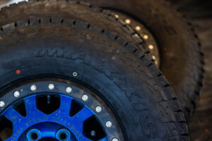 A close-up view of Maxxis tires mounted on bright blue racing wheels.