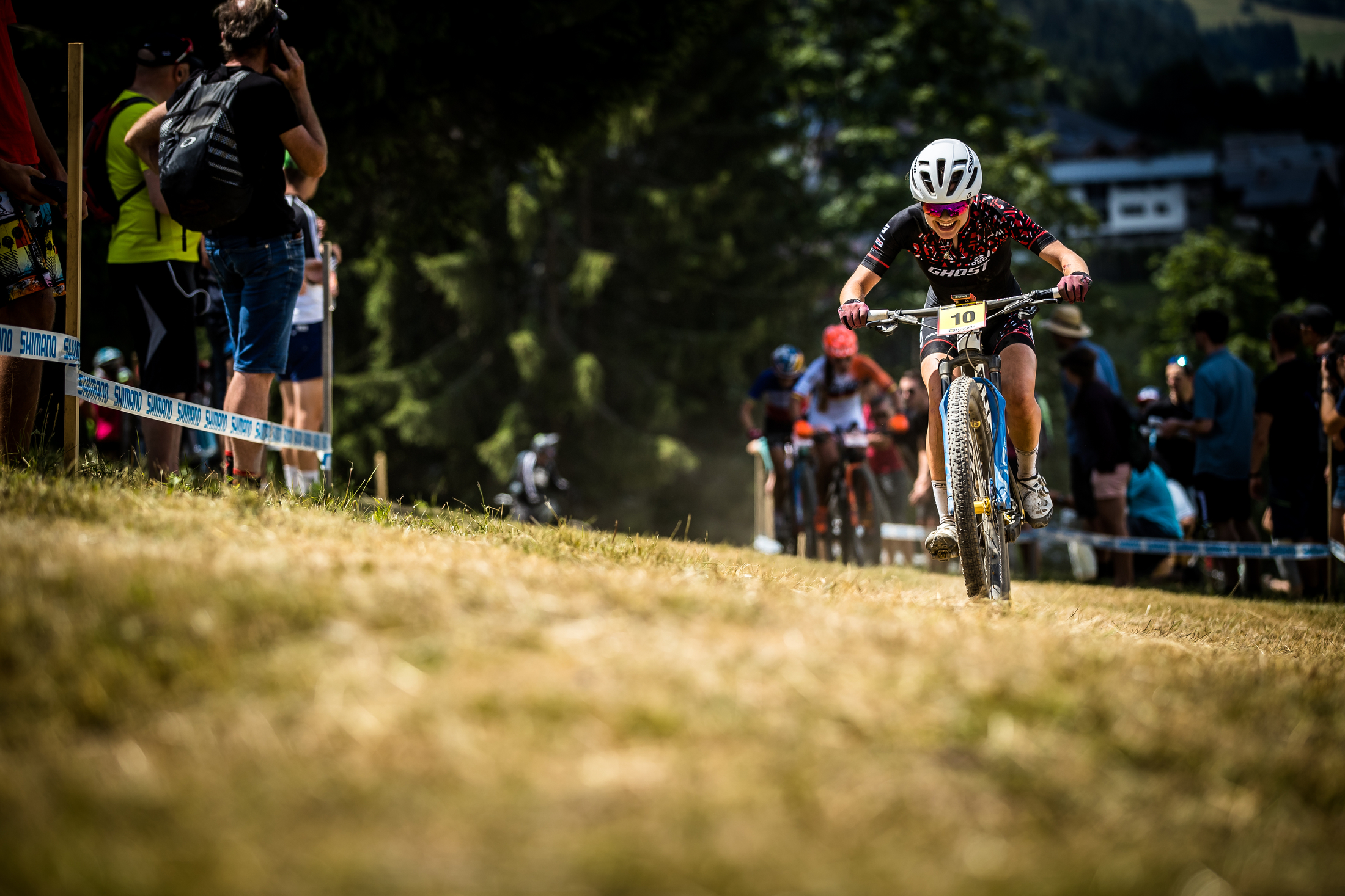 Frei pedals across a grassy flat with a smile on her face.