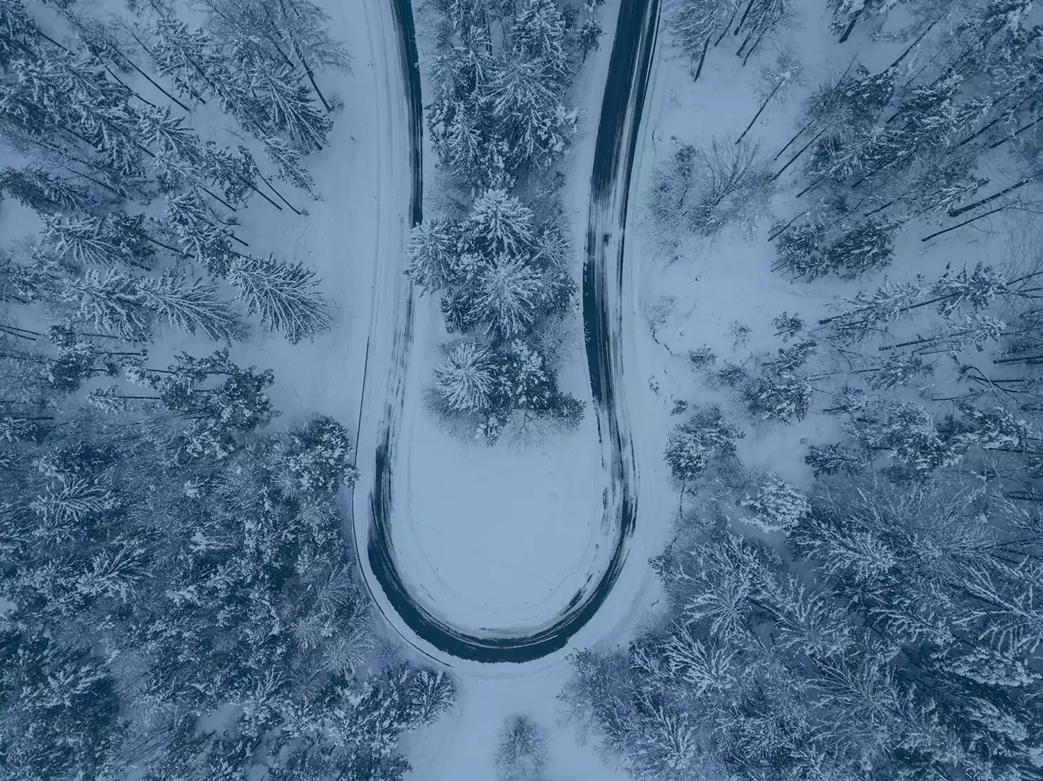 Aerial view of snow and ice-covered rural road.