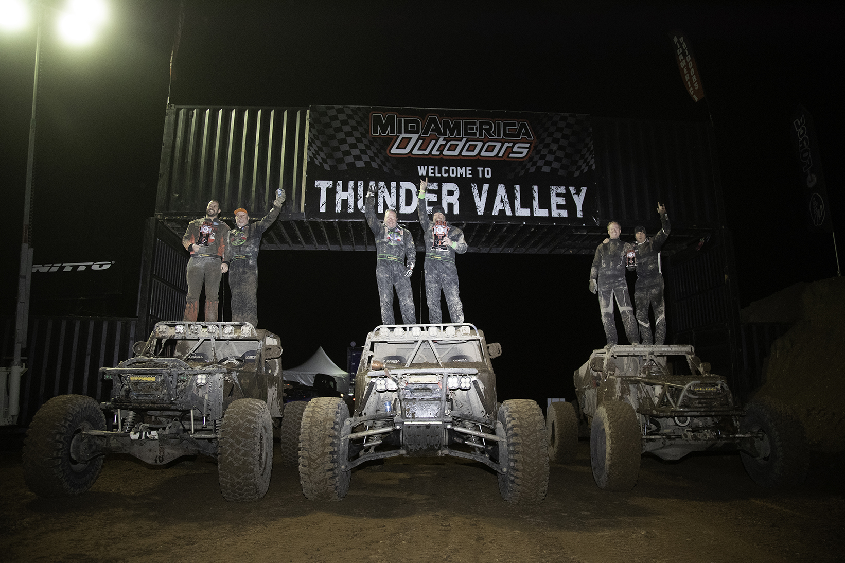 three trucks with their drivers celebrating on the hoods