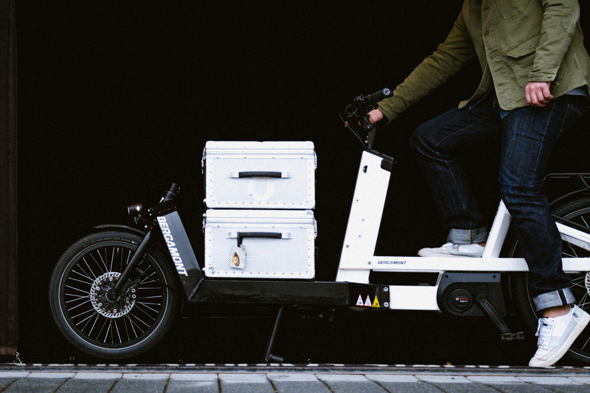 An electric cargo bike loaded with silver cases.