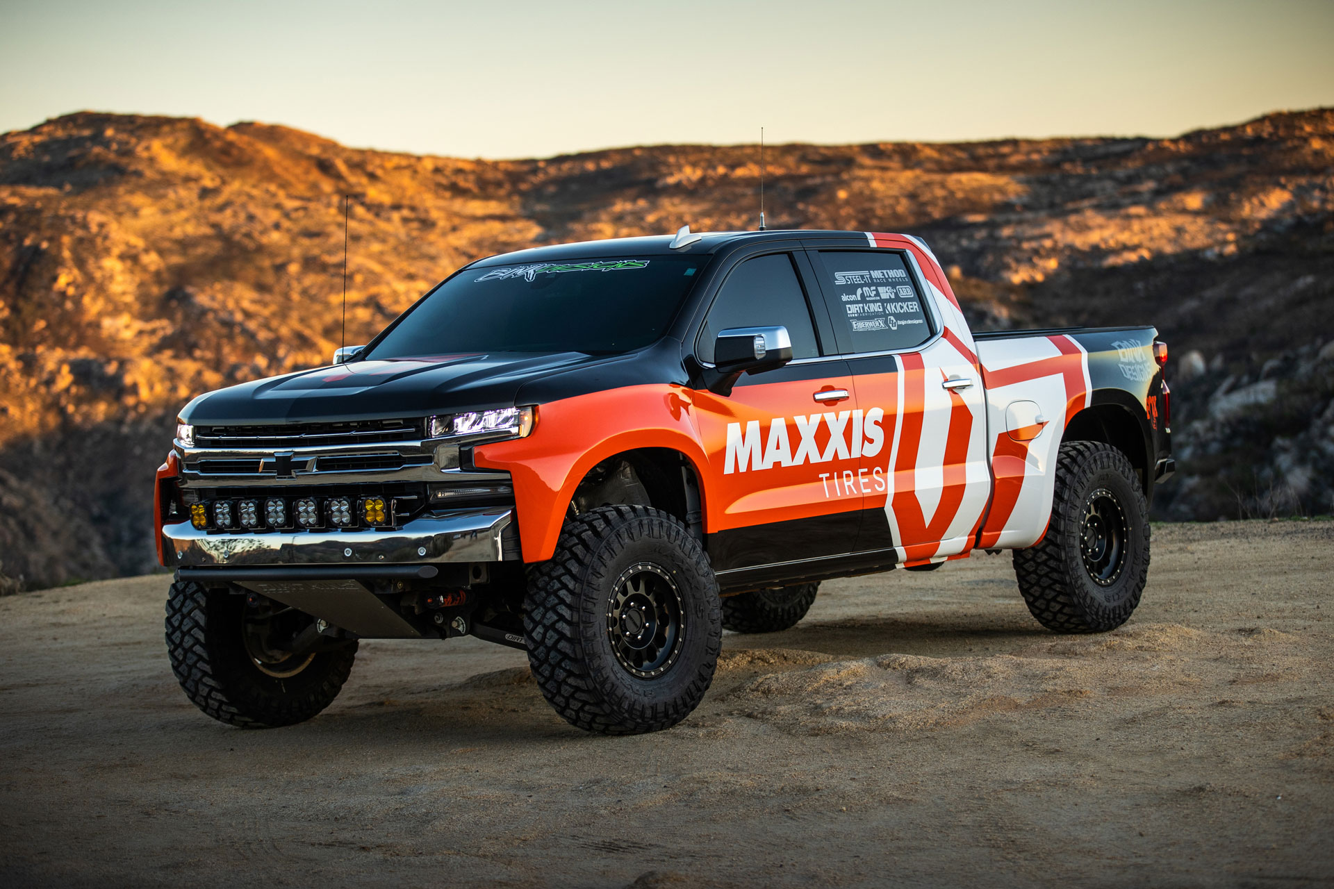 Chevy Truck with Maxxis livery on Maxxis RAZR MT tires on sand, static image.