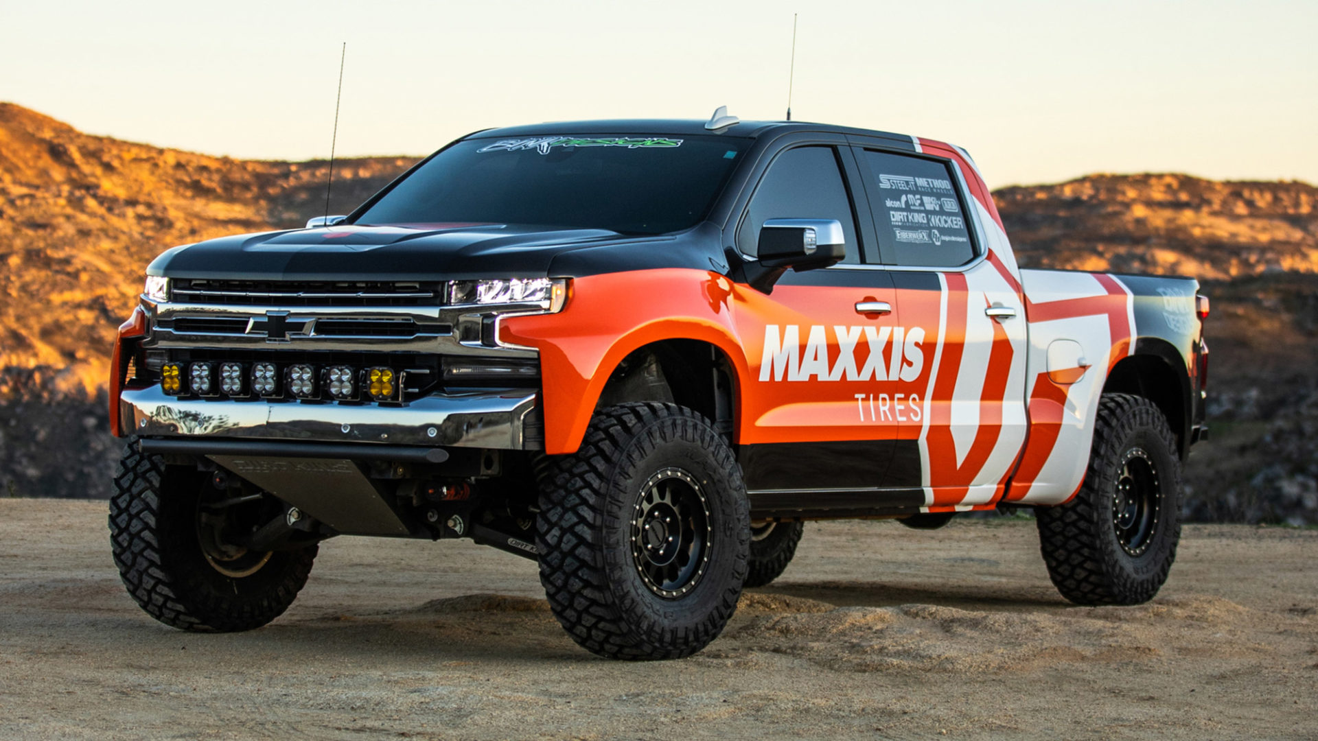 Chevy Truck with Maxxis livery on Maxxis RAZR MT tires on sand, static image.