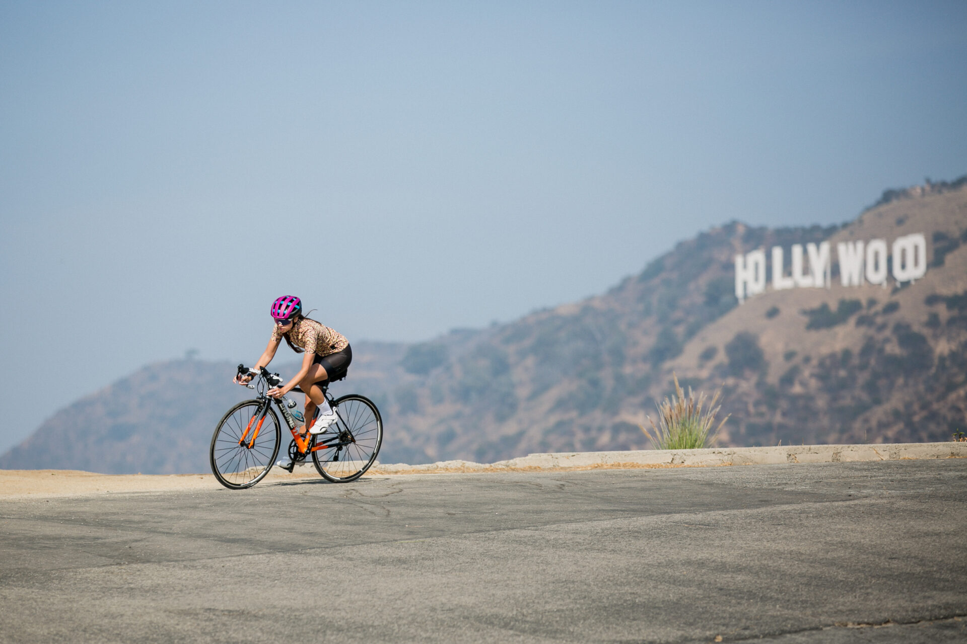 Rider pedaling by the Hollywood sign