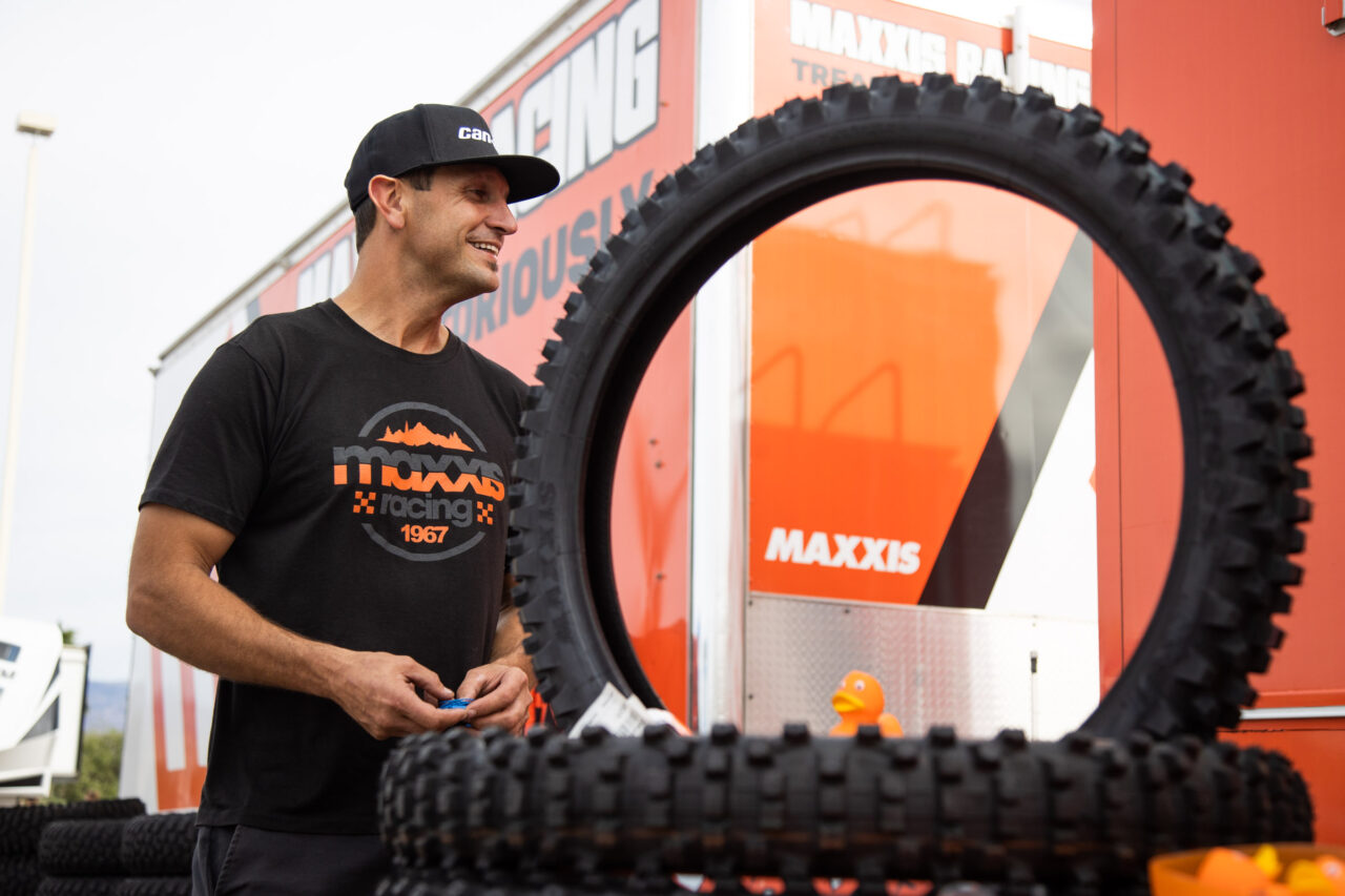 Maxxis rider Ranuio Jones next to Maxxis Racing toterhome hauler truck and Maxxis Maxxcross tires on display