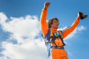 Adrian Cenni with his fists raised in the air with blue sky in the background.
