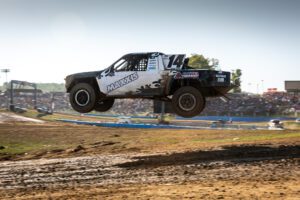 Black and white race truck mid-flight at crandon raceway.