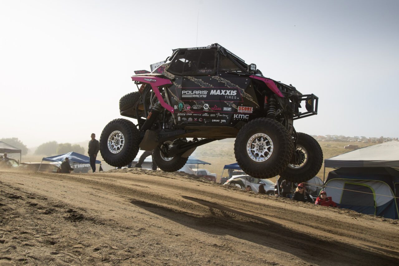 Pink and Black SxS mid-flight off a jump.