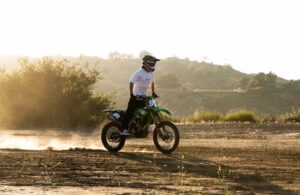Axell Hodges in Ethika street clothes riding his dirbike across a flat dirt surface at his compound in CA.