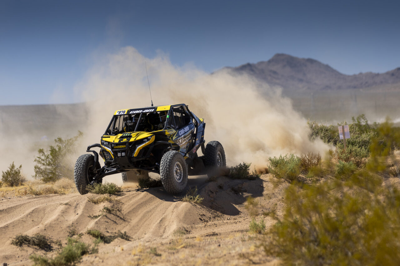 Maxxis sponsored UTV with a dust cloud following.
