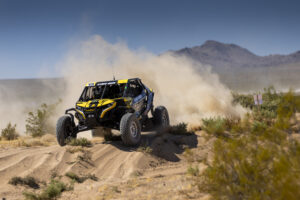 Maxxis sponsored UTV with a dust cloud following.