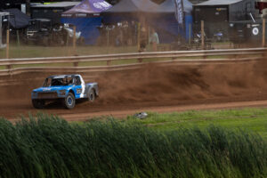 Maxxis truck throwing up some dirt on the track.