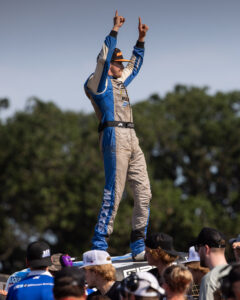 Trey Gibbs standing on top of his race truck celebrating after a win in Champ OffRoad Short Course racing.