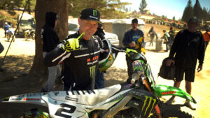 Jeremy McGrath holding up a number one finger standing with his motorcycle.