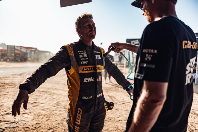 Andrew Short with Arms wide open while his mechanic dusts him off with an air hose.