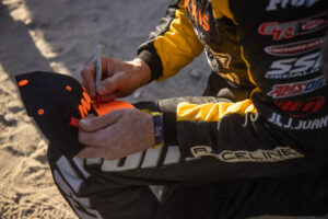 A tight shot of Kyle Chaney Signing a Maxxis podium hat.