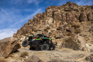 Jeremy McGrath in his Green KRX SxS boosting up a rocky embankment.