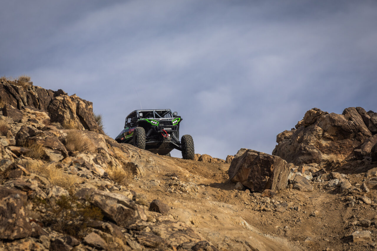 Jeremy McGrath in his Green KRX SxS craling through some rocks.