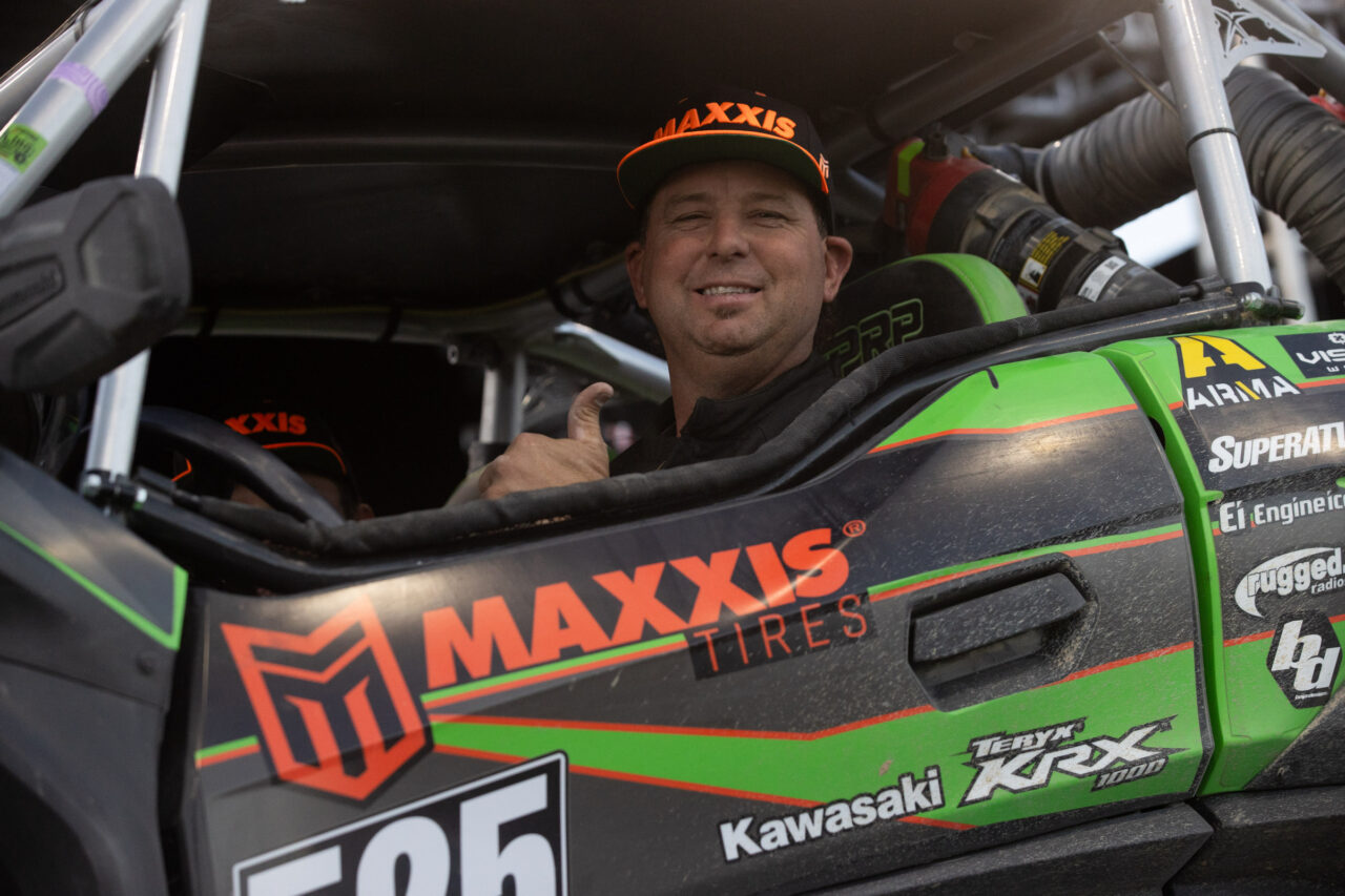 McGrath with a thumbs up while seated in his KRX driving his race winning car up onto the podium.