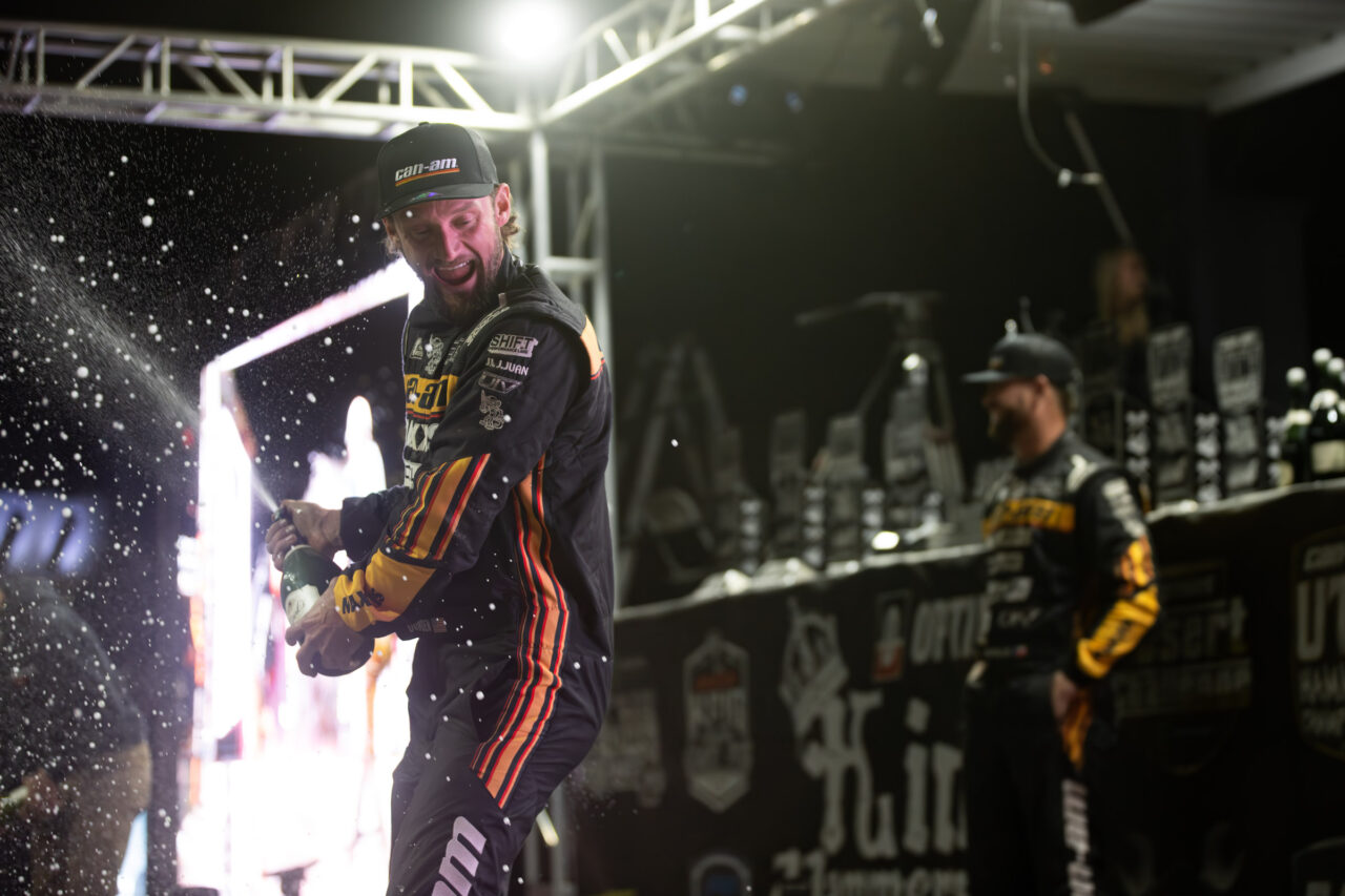 Cody Miller on the KOH podium poping champagne while celebrating his win.