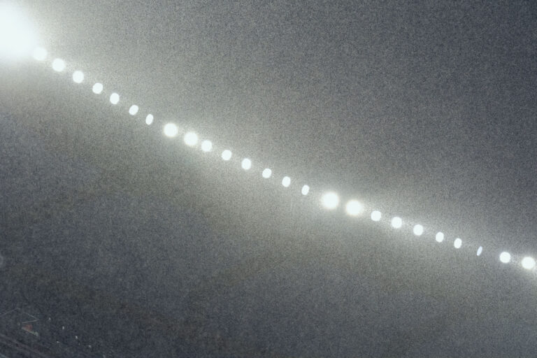 View looking up at the stadium lights as heavy rain falls.