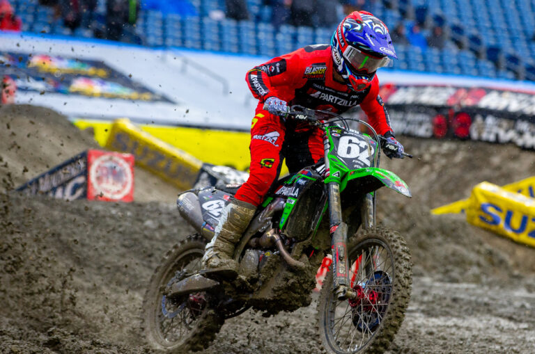 PRMX Maxxis Racer covered in mud while racing his green dirtbike in 250 SX.