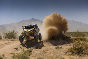 Cody Bradburry Rockets his CanAm SxS off of a sand wash berm with dust plum exploding behind him.