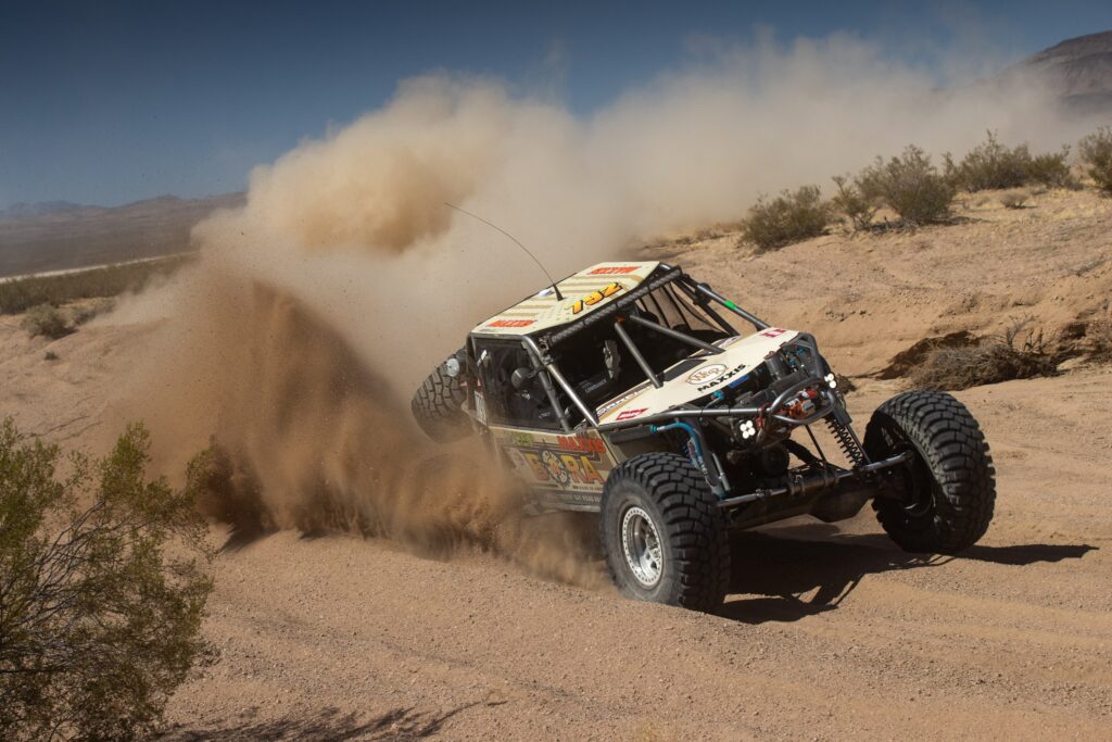 Maxxis athlete throwing up dust in a curve