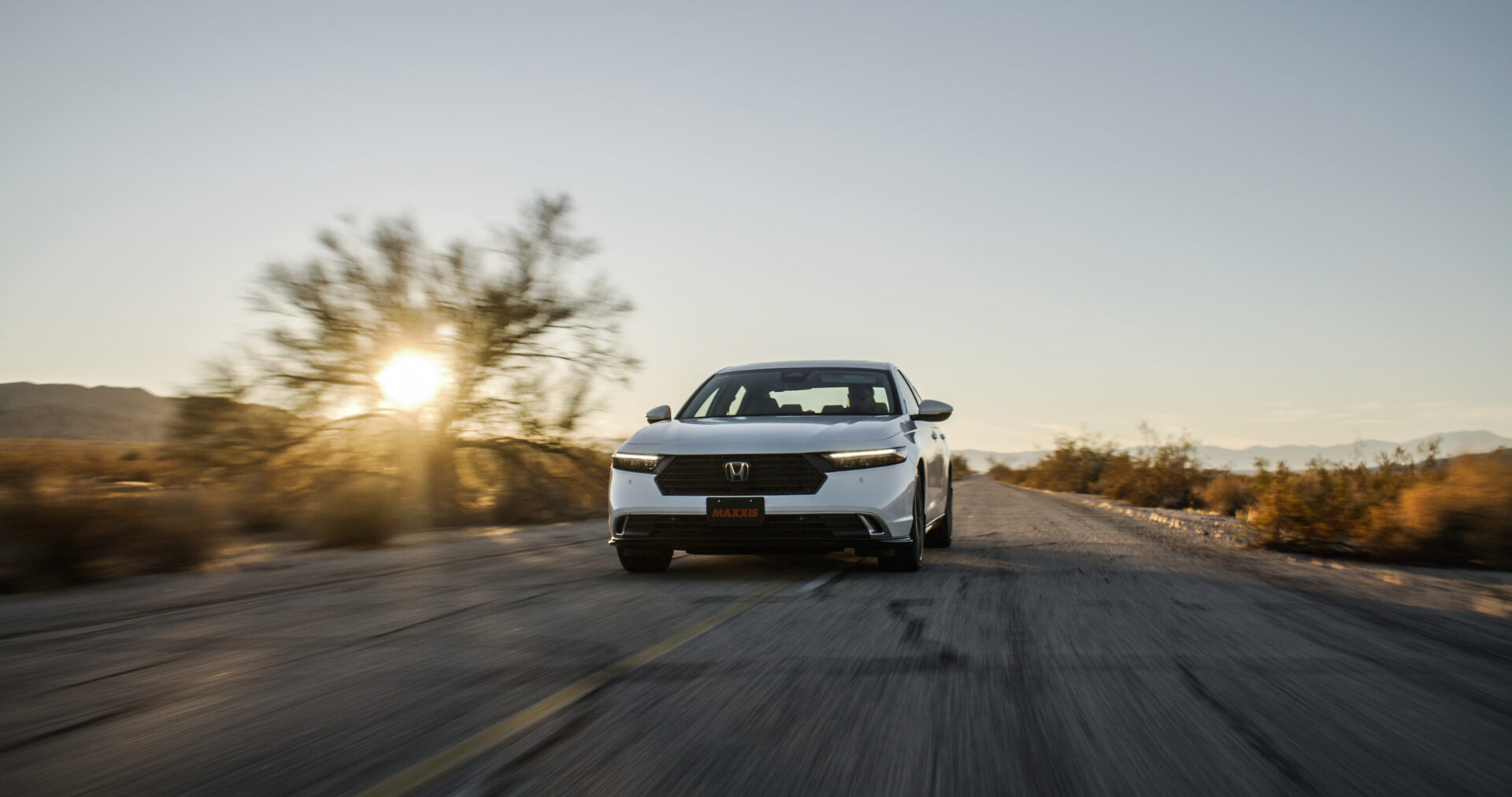 Honda, driving on rural road near sunset.
