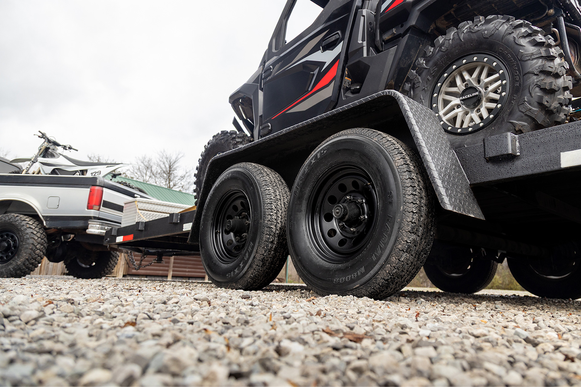 Trailer with SXS being pulled by a truck. Focus is tight on the trailer tires.