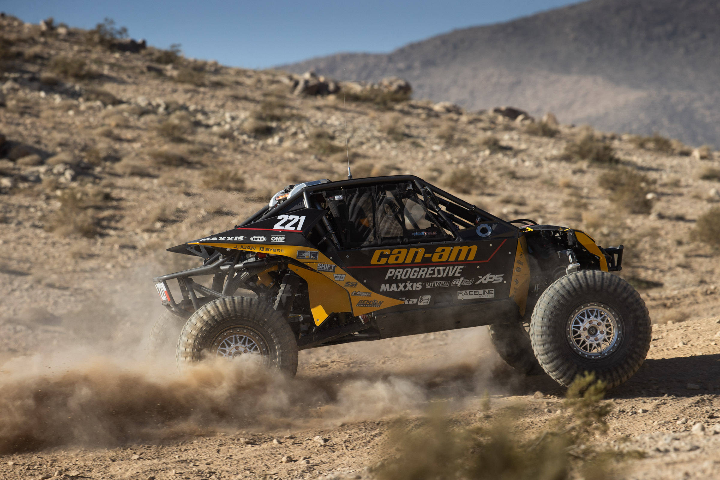 yellow and black CanAm boosting at full speed in the desert.