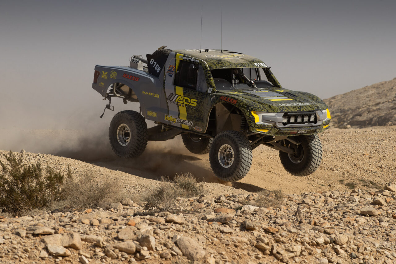 TT Eco Diesel For race track with three of four wheels off the ground as it crests a hill on the 2026 KOH Desert Challenge race course.