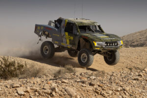 TT Eco Diesel For race track with three of four wheels off the ground as it crests a hill on the 2026 KOH Desert Challenge race course.