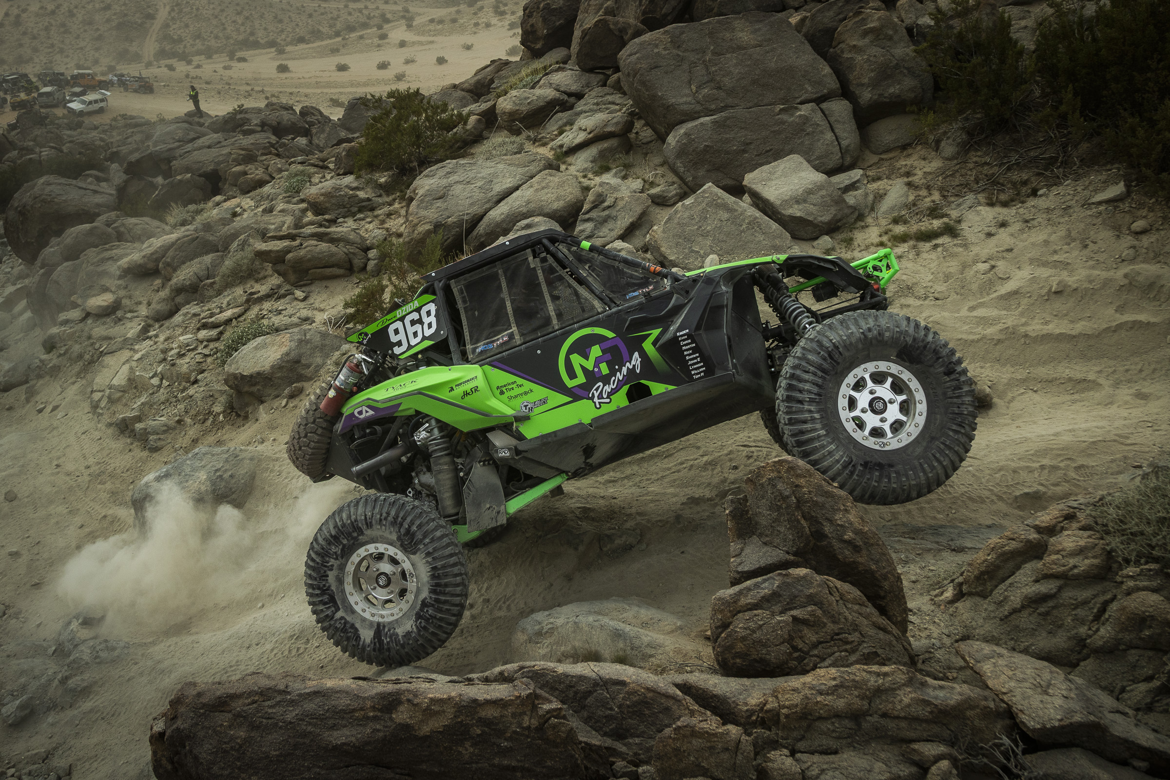 Un SxS vert et noir naviguant sur de gros rochers avec des pneus Maxxis Super Knobby Roxxzillas.