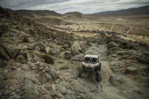 Maxxis athlete Jeremy McGrath racing up a rocky path in his red and black KRX SxS.