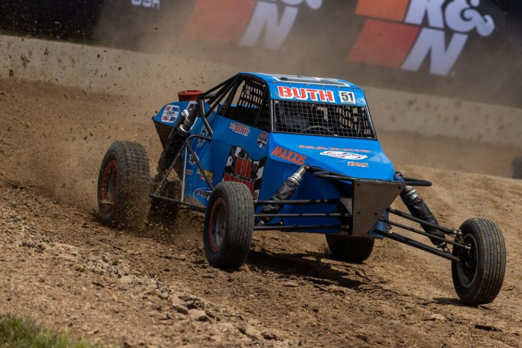 Maxxis athlete in a buggy on track, moving quickly