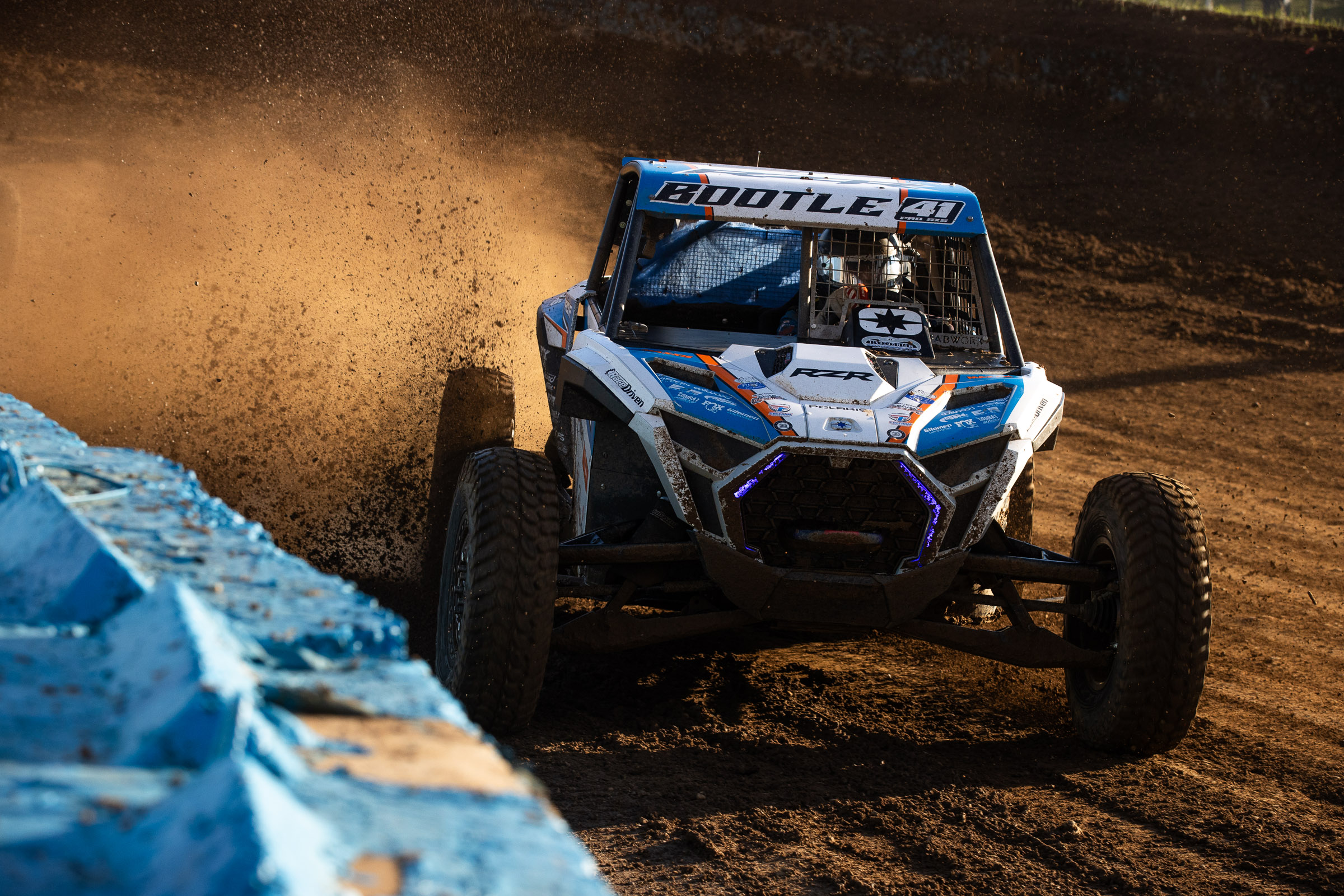 a polaris sxs hugging the K rail on the inside of a dirt turn at Crandon offroad raceway.
