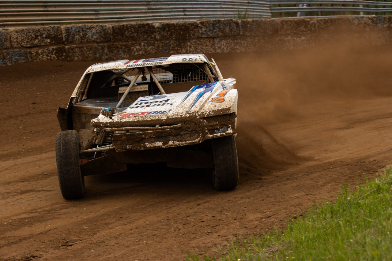 Jimmy Henderson exiting a corner with speed in his white united rentals/MAXXIS pro4 truck.