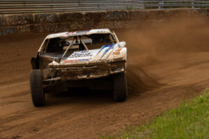 Jimmy Henderson exiting a corner with speed in his white united rentals/MAXXIS pro4 truck.