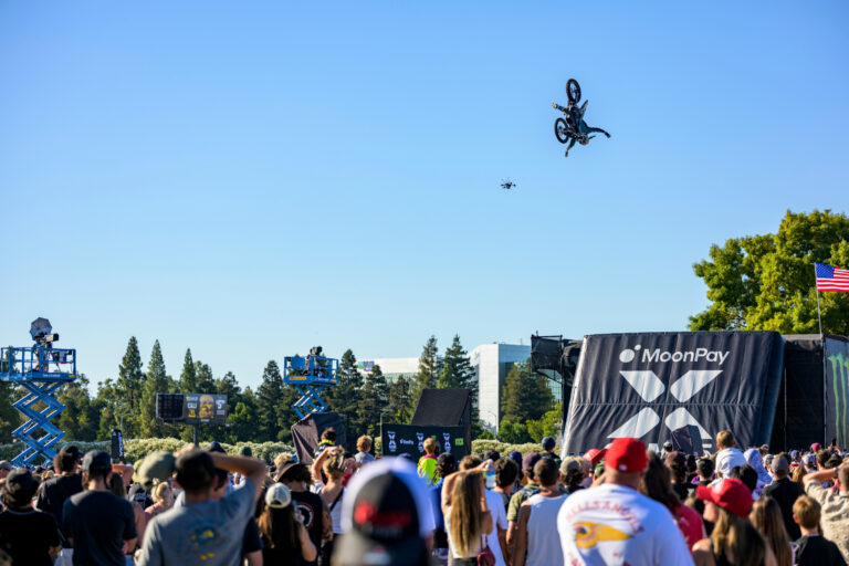 Dirt Bike Rider in mid-air flight. A black inflatable landing ramp is in view for the rider to land on.