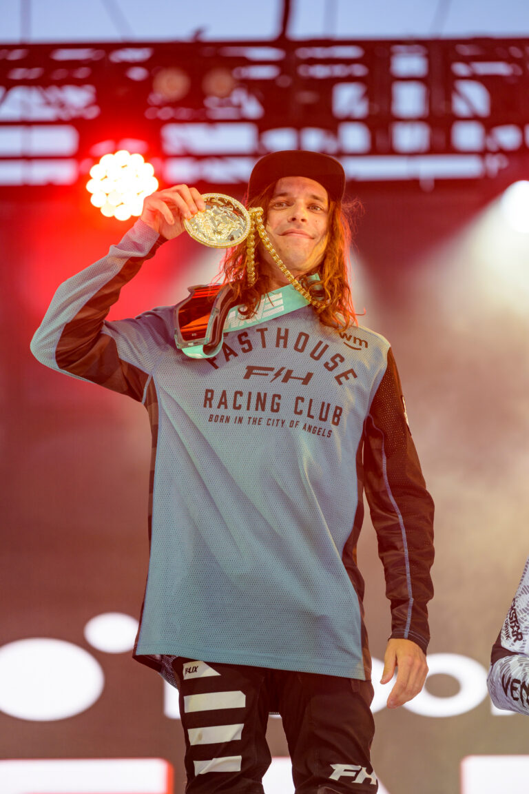 Pat Evans posing next to his gold X Games medal on the podium.
