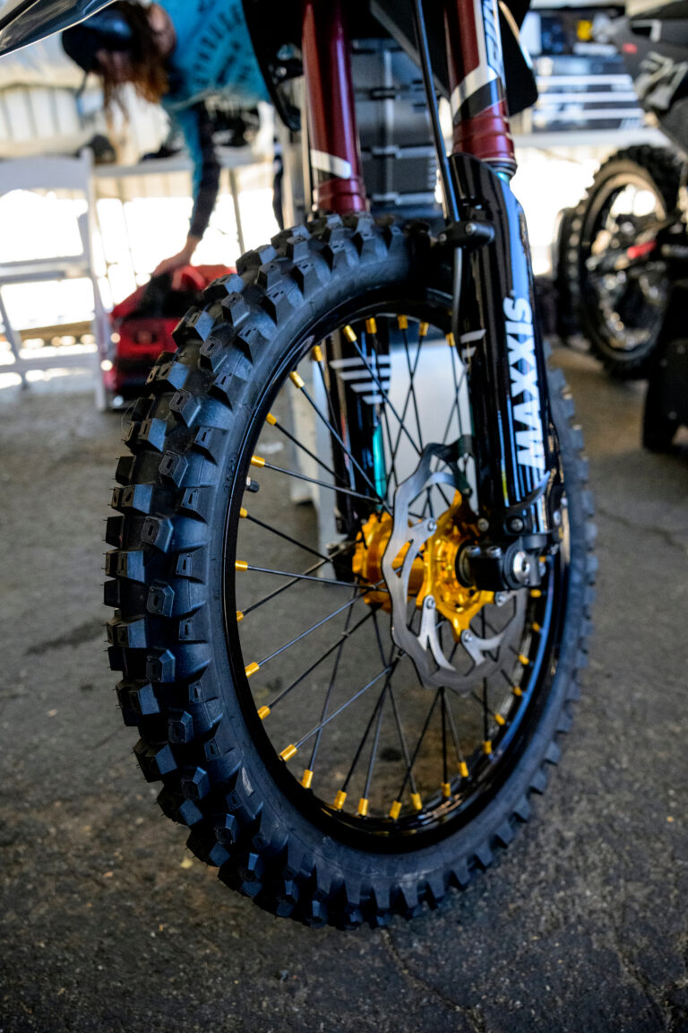 a front dirtbike tire with MAXXIS clearly displayed on a black plastic fork guard.
