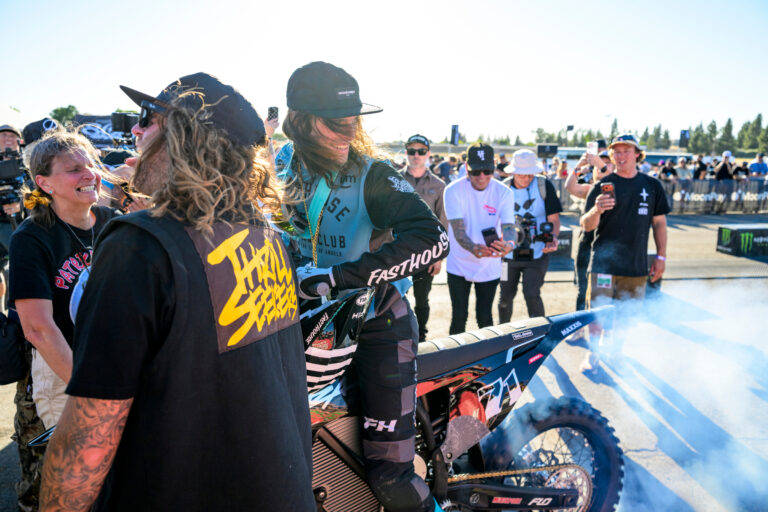 Patrick Evans in teal and black on his dirt bike surrounded by fans.